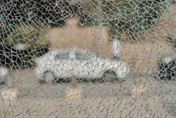 Close-up of a shattered glass pane with shatter protection film holding the glass together and preventing injuries from splinters.